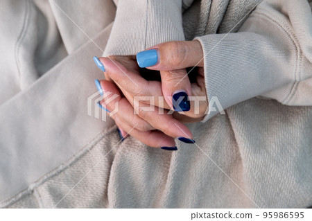Gel nail design.Beautiful manicure. Nail polish is applied to the hand, polish is a blue color. Blue background closeup. Multi-colored blue manicure. 95986595