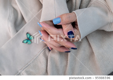 Gel nail design.Beautiful manicure. Nail polish is applied to the hand, polish is a blue color. Blue background closeup. Multi-colored blue manicure. 95986596