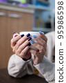 Gel nail design.Beautiful manicure. Nail polish is applied to the hand, polish is a blue color. Blue background closeup. Multi-colored blue manicure. 95986598