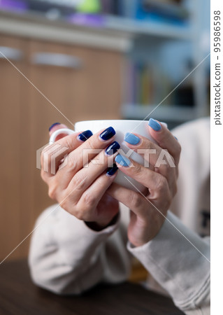 Gel nail design.Beautiful manicure. Nail polish is applied to the hand, polish is a blue color. Blue background closeup. Multi-colored blue manicure. 95986598