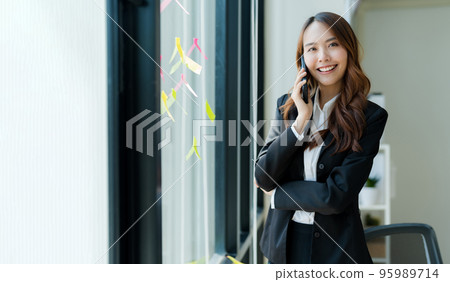 Happy young asian business woman wearing suit holding mobile phone 95989714