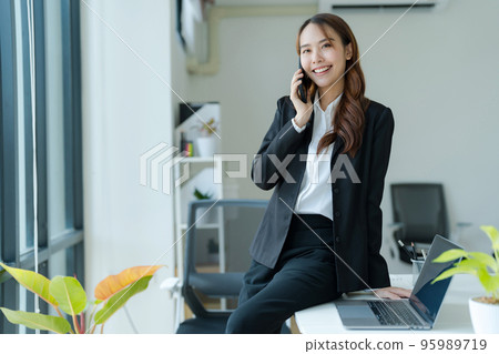 Happy young asian business woman wearing suit holding mobile phone 95989719