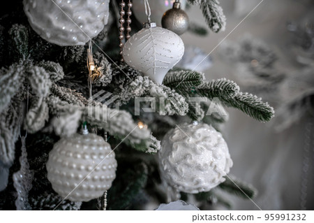 Close-up of a festively decorated outdoor Christmas tree with balls on a blurred sparkling fairy background. Defocused garland lights, bokeh effect. Close-up of a festively decorated outdoor Christmas tree with balls on a blurred sparkling fairy background. Defocused garland lights, bokeh effect. 95991232