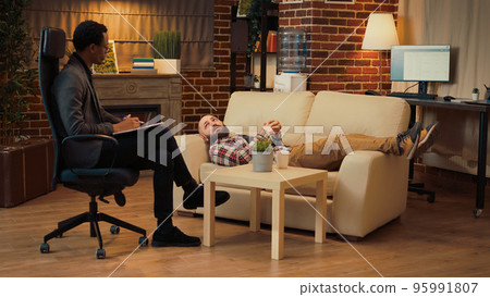 African american therapist listening to patient at counseling session, talking about marriage conflict and and problems. Specialist consulting person laying on couch in office. African american therapist listening to patient at counseling session, talking about marriage conflict and and problems. Specialist consulting person laying on couch in office. 95991807