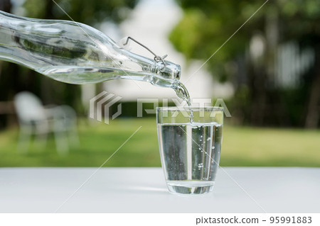 Pour the water from the water bottle into the glass. 95991883