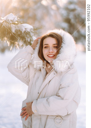 Beautiful woman in winter clothes posing in a snowy park. Young lady walking in a sunny winter day. Beautiful woman in winter clothes posing in a snowy park. Young lady walking in a sunny winter day. 95992102