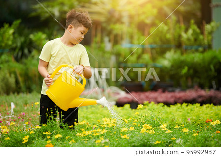 Little boy watering plants in gardening center on sunny day Little boy watering plants in gardening center on sunny day 95992937