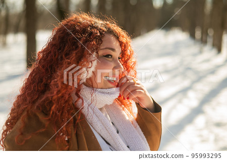 Cheerful fat caucasian woman in fur headphones outdoors.  95993295