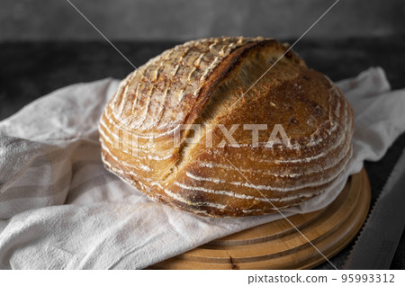 Homemade sourdogh whole round bread on dark background. Home baking concept. Homemade sourdogh whole round bread on dark background. Home baking concept. 95993312