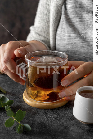 Black tea in glass cup, morning hot drink. Tea bag. Lifestyle, moody photo Black tea in glass cup, morning hot drink. Tea bag. Lifestyle, moody photo 95993315