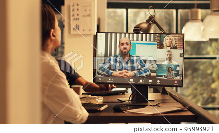 Corporate employee talking to people on online videocall conference, attending startup briefing videoconference meeting on webcam. Working at sunset, chatting on remote teleconference. 95993921