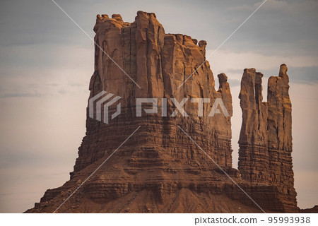 View of beautiful rock formations at famous Monument Valley in desert. Geological features amidst remote landscape with cloudy sky in background. Tourist attraction in Navajo Tribal Park. 95993938