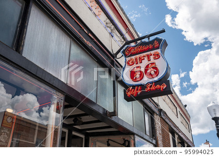 Williams, USA. September 16, 2022. Creative electric signboard with text and number on store with cloudy sky in background. Banner hanging on gift shop at Route 66 in city of Williams during summer. 95994025