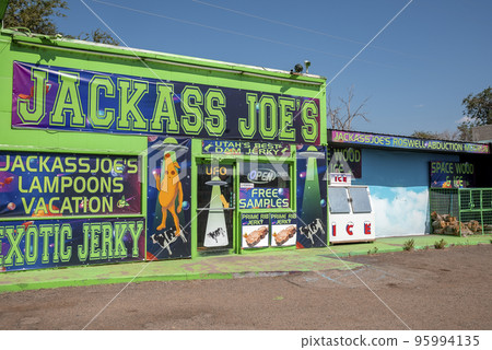 Arizona, Usa, September 16,2022. Jackass Joe's Sign With Ufo Posters On Store's Wall Of Modern Gas Station on a Sunny Day 95994135