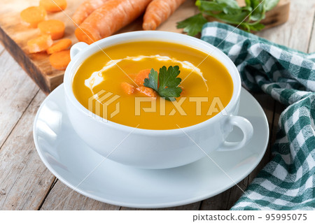 Carrot soup with cream and parsley on wooden table. Close up 95995075