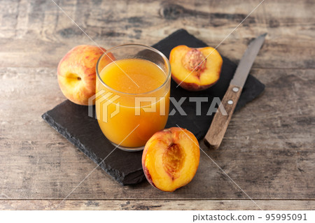 Natural peach juice in glass on wooden table 95995091