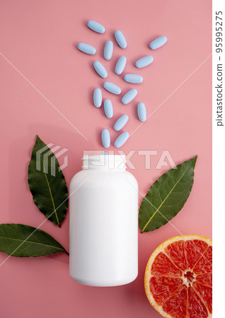 Natural food supplements pills, white plastic bottle with vitamins, pink background and sun light with shadows. Natural food supplements pills, white plastic bottle with vitamins, pink background and sun light with shadows. 95995275