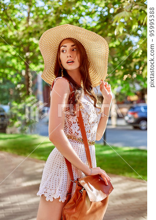 Sunny lifestyle fashion portrait of young stylish hipster woman walking on the street, wearing trendy outfit, straw hat, travel with backpack. 95995388