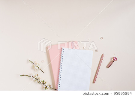 A blank notebook sheet with a sprig of white apple blossoms, a pink notebook and a pink pen on a beige background. Spring concept for a blog with copy space A blank notebook sheet with a sprig of white apple blossoms, a pink notebook and a pink pen on a beige background. Spring concept for a blog with copy space 95995894