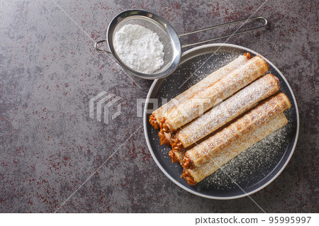 Waffle tubule with boiled condensed milk closeup on plate. Horizontal top view 95995997
