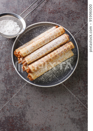 Waffles cones with boiled condensed milk in plate on table. Vertical top view 95996000