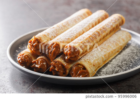 Waffle tubule with boiled condensed milk closeup on plate. Horizontal Waffle tubule with boiled condensed milk closeup on plate. Horizontal 95996006