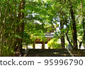 The entrance of a temple lined with green trees 95996790