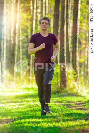 Man jogging in city partk at beautiful summer day. Sport fitness model caucasian ethnicity training outdoor. 95996899
