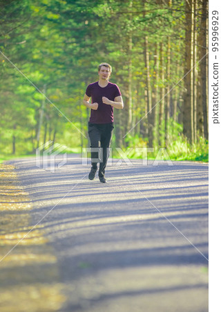 Man jogging in city partk at beautiful summer day. Sport fitness model caucasian ethnicity training outdoor. 95996929
