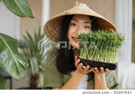 Portrait of young asian woman holding microgreen sprouts on tropical exotic background Portrait of young asian woman holding microgreen sprouts on tropical exotic background 95997641