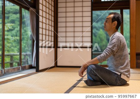 一名中年男子在旅途中從下榻的客棧的窗戶望著外面的景色 95997667