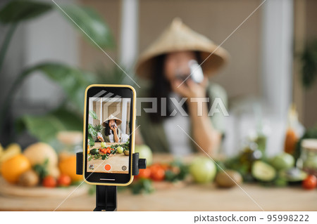 Beauty asian blogger in traditional conical hat using dates to make healthy salad for breakfast Beauty asian blogger in traditional conical hat using dates to make healthy salad for breakfast 95998222