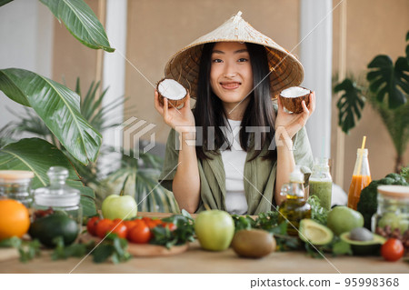 Beautiful asian young woman cooking fresh organic healthy food using coconut Beautiful asian young woman cooking fresh organic healthy food using coconut 95998368