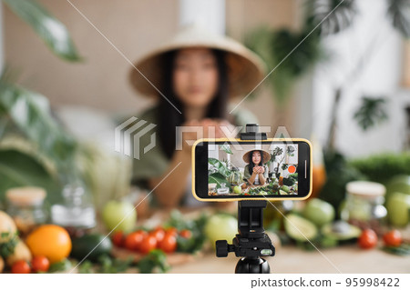 Beauty asian blogger in traditional conical hat using coconut to make smoothies for breakfast 95998422