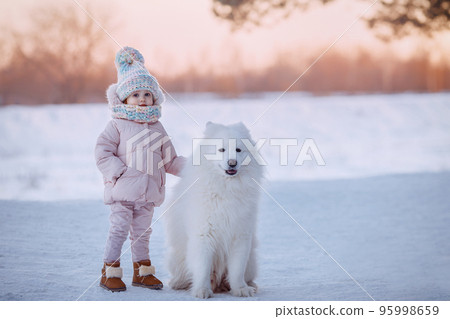 Charming little girl in a warm coat with a dog Charming little girl in a warm coat with a dog 95998659