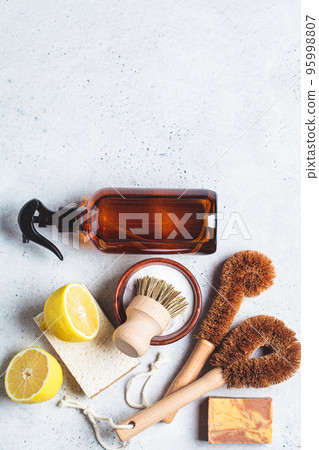 Zero waste eco friendly products and tools for house cleaning. Wooden brushes, coconut sponges, spray vinegar, soda, lemon and organic soap, gray background. 95998807