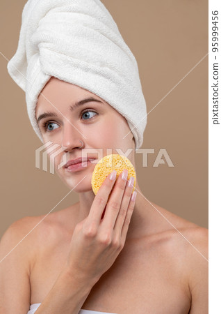 Pretty young girl cleaning her face with a sponge 95999456