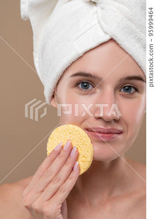Pretty young girl cleaning her face with a sponge 95999464