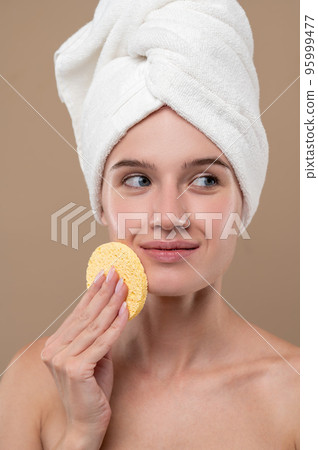 Pretty young girl cleaning her face with a sponge Pretty young girl cleaning her face with a sponge 95999477