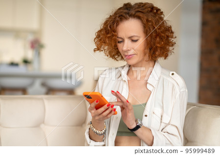 Cute ginger woman with a smartphone in hands Cute ginger woman with a smartphone in hands 95999489