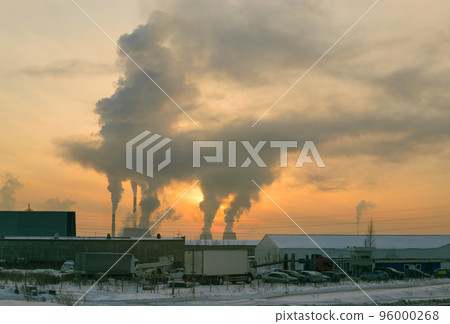 The smoke from the CHP chimneys blocked the sun in the evening sky at sunset. In the foreground is a parking lot with a white truck on it. The smoke from the CHP chimneys blocked the sun in the evening sky at sunset. In the foreground is a parking lot with a white truck on it. 96000268