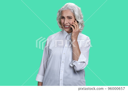 Portrait of aged old woman talking on phone. Isolated over pastel green background. 96000657