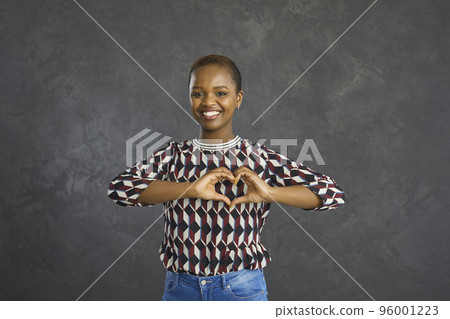 Portrait of a young African American woman forming a heart symbol with her hands 96001223
