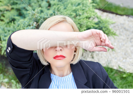 Depressed. Woman covers her face with her hand from fatigue in the middle of the working day Depressed. Woman covers her face with her hand from fatigue in the middle of the working day 96001501