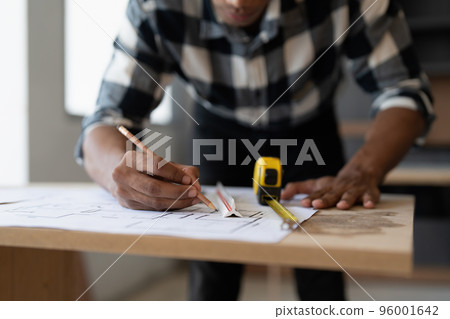 Architect man working with blueprints for architectural plan, engineer sketching a construction project, green energy concept 96001642