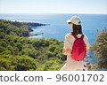 The young woman with pink backpack is standing against mediterranean sea coast nature during the hike. 96001702