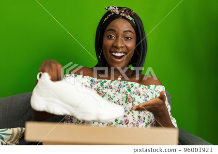 African young woman sit on couch at home unpack cardboard box with online purchase African young woman sit on couch at home unpack cardboard box with online purchase 96001921