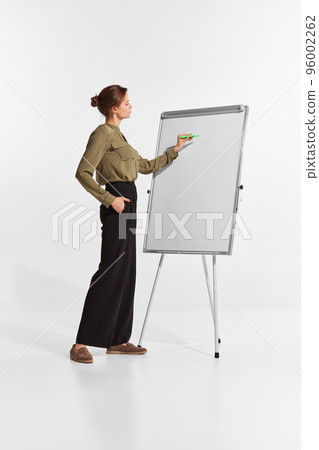 Portrait of young woman, manager, team leader writing tasks on flipchart isolated over white background 96002262