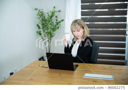 A woman looking at a computer in the office and looking suspicious 96002275
