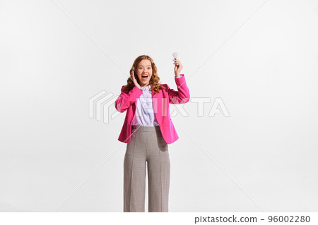 Portrait of young happy woman, employee holding light bulb symbolizing new professional idea isolated over white background Portrait of young happy woman, employee holding light bulb symbolizing new professional idea isolated over white background 96002280